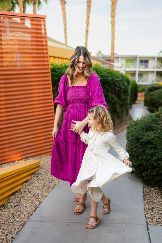 Mother guiding daughter while she twirls dress during Burlingame mommy and me photographer spring portrait session