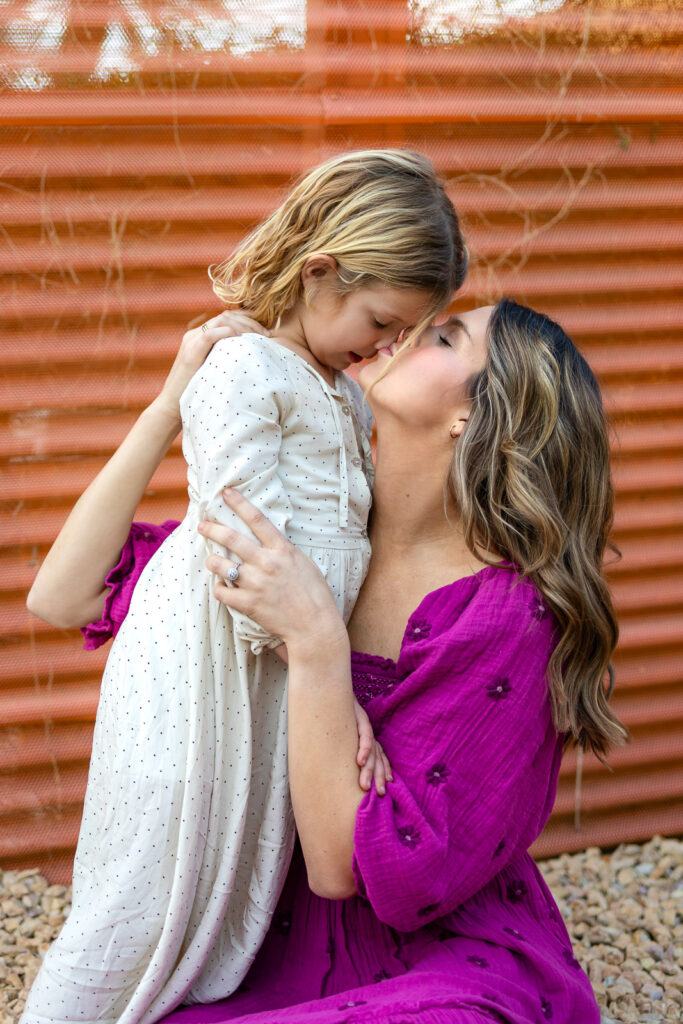 Mother smiling up at daughter while holding her during Burlingame mommy and me photographer lifestyle session