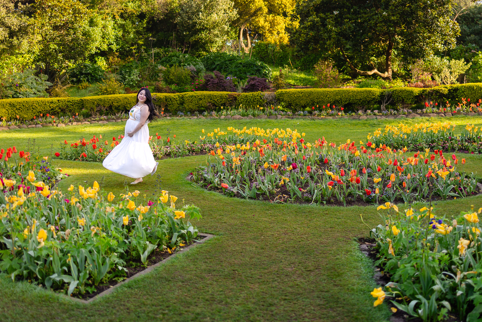 A wide landscape view of a family standing among thousands of red and yellow tulips at the Queen Wilhelmina Garden during peak spring bloom.