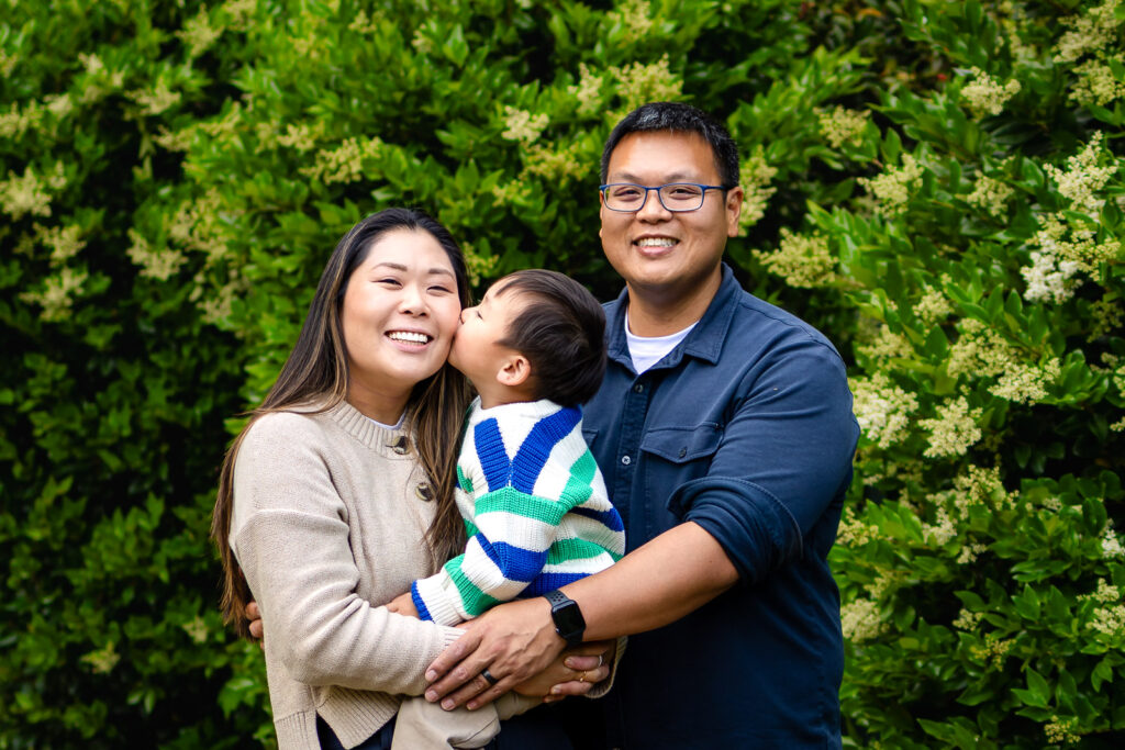 A connection-filled moment of parents laughing with their toddler, captured during a low-pressure garden session in Palo Alto.