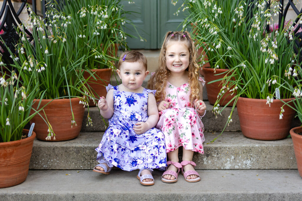 Close-up of a young girls in a floral dress leaning down to smell vibrant spring flowers, showcasing the kid-friendly environment of Filoli.