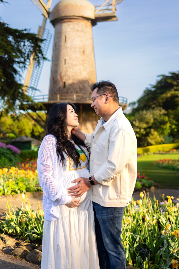A couple embracing on the bluffs of Mori Point in Pacifica during a sunset maternity session, showcasing a well-led and natural photography experience.