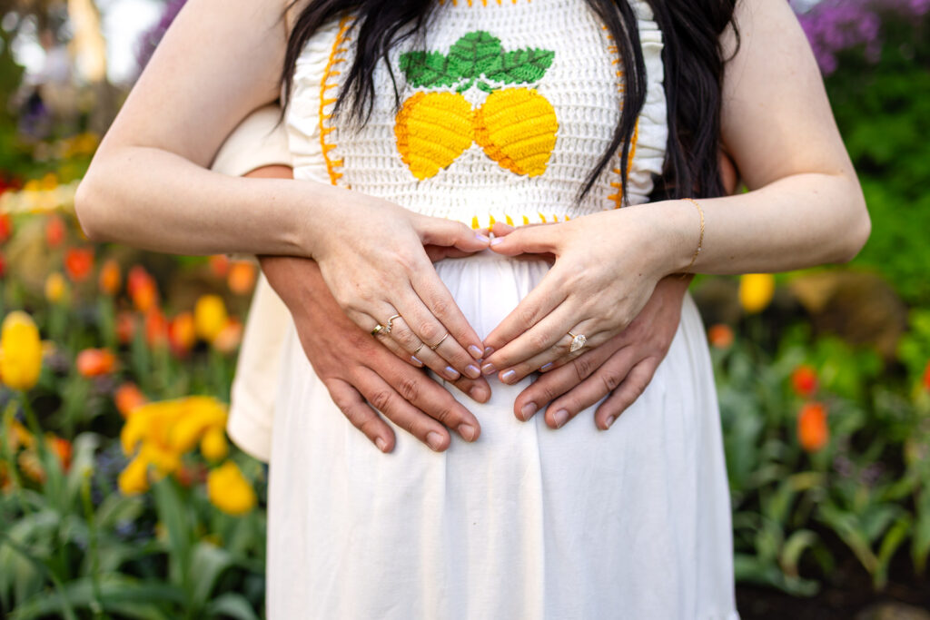 A close-up detail of a mother’s hands on her baby bump during a golden hour maternity session on the San Francisco Peninsula, emphasizing a calm and guided style