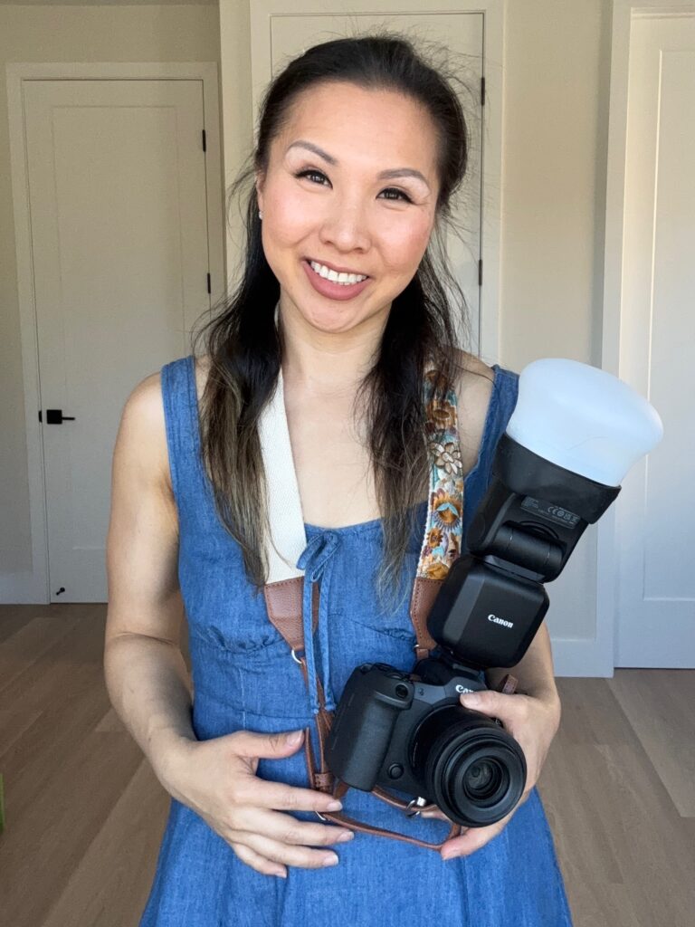 San Mateo family photographer Ellen Lai smiling and holding a professional Canon camera with a flash, representing her guided and expert approach to photography.