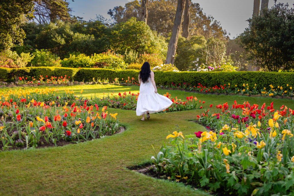 A woman walking through rows of vibrant tulips near Ocean Beach in San Francisco during peak bloom.