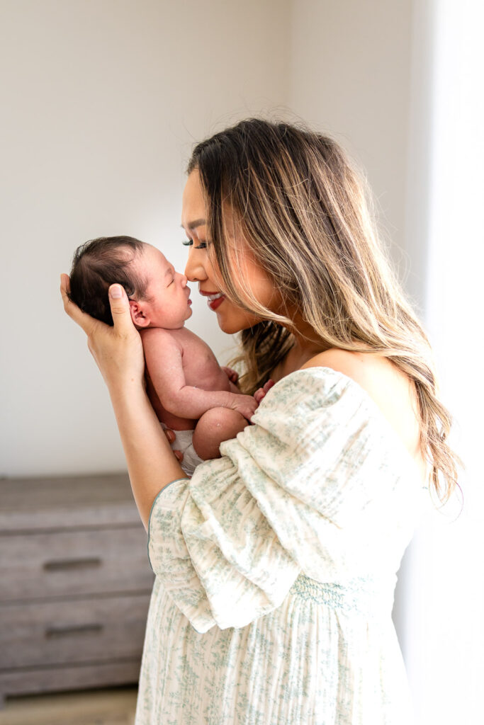 A mother holding her newborn baby in a profile pose, showcasing the calm leadership and flattering, guided direction that defines a premium SF Peninsula family session.