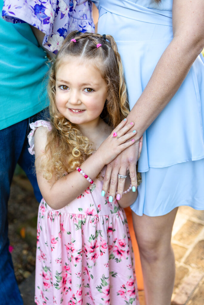 A close-up portrait of a young girl surrounded by pink and purple tulips at Filoli Gardens.