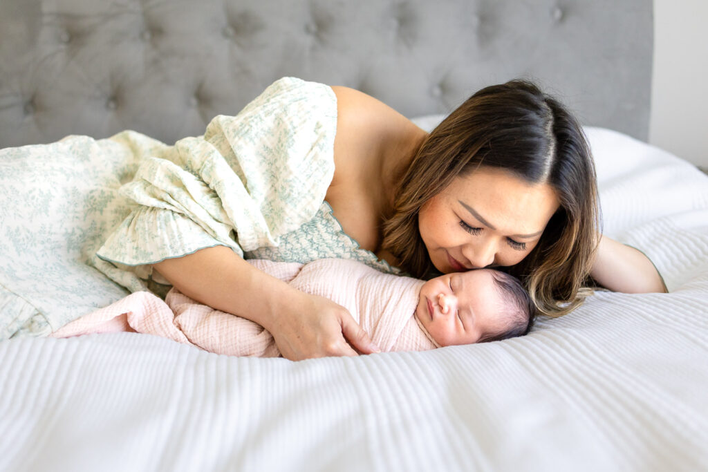 A sleeping newborn baby lying on a white bed during an in-home session, illustrating the professional quality and artistic consistency Peninsula families expect when researching newborn photography cost.