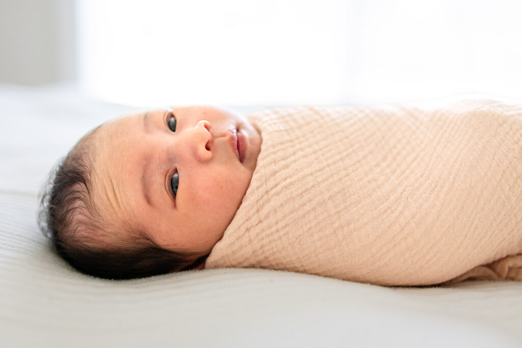 A close-up of a swaddled newborn baby's face, demonstrating the artistic consistency and professional safety standards that impact newborn photography cost in the Bay Area.