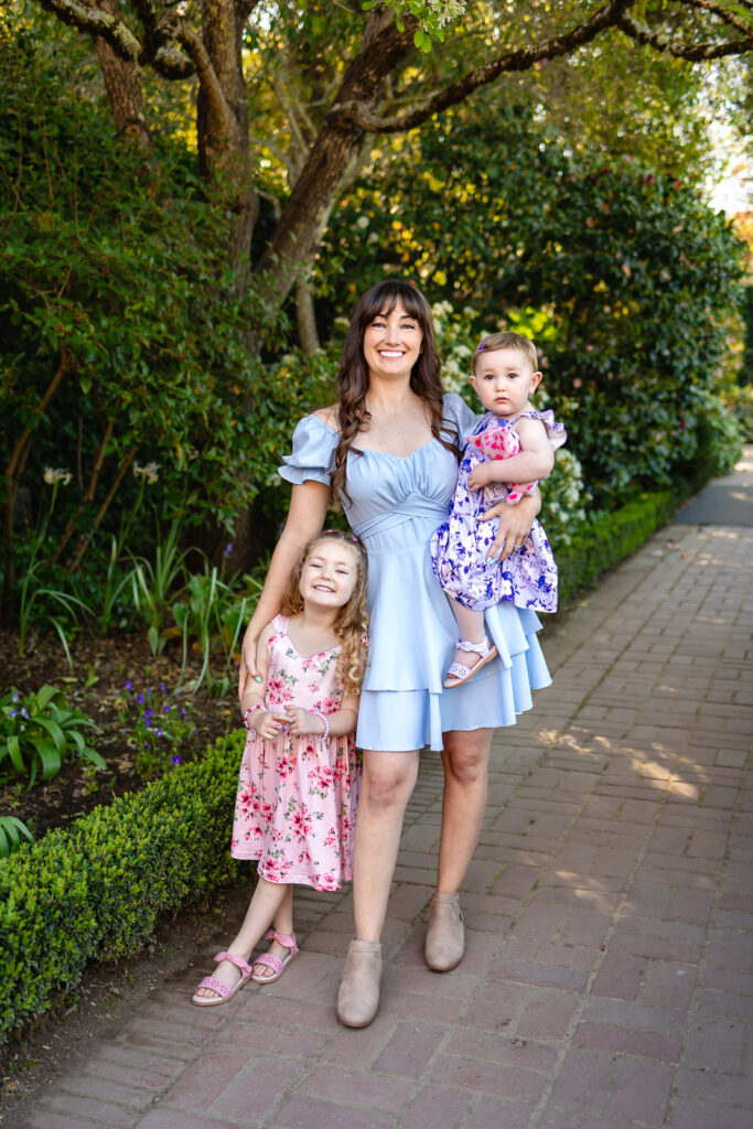 A mother and daughter walking through the Filoli estate gardens wearing soft blue and floral spring outfits.