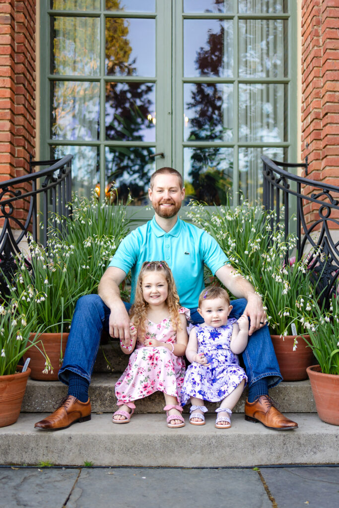 Two young girls in spring dresses sitting together in the manicured gardens at Filoli in San Mateo County.