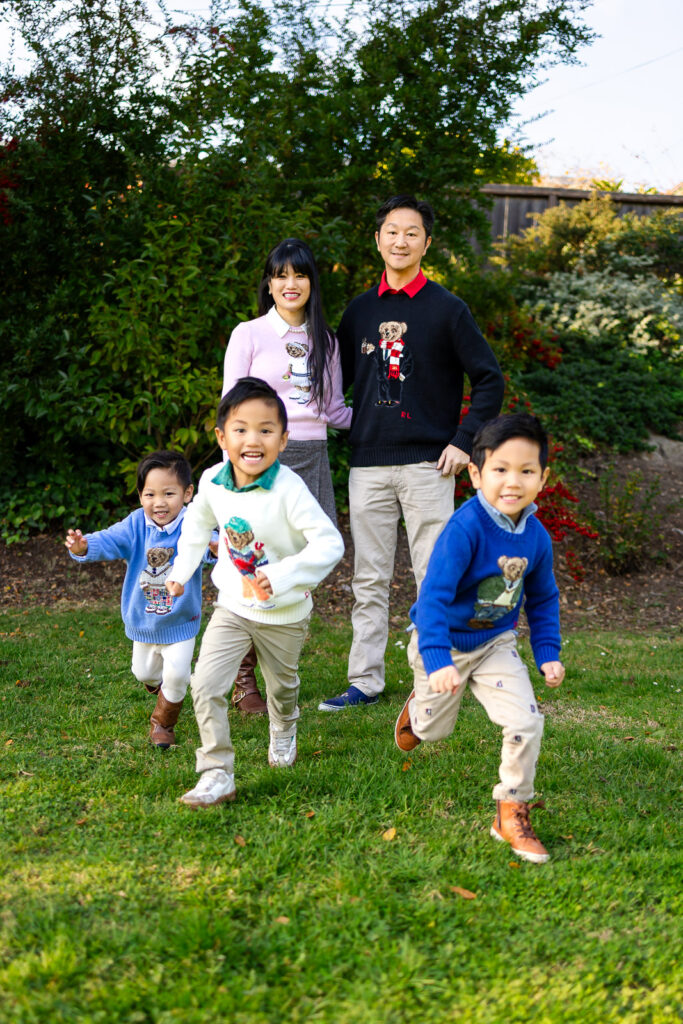 A family running toward the camera in a sunny park at Millbrae Meadows.
