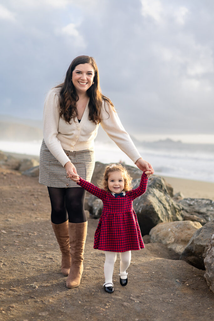 A Bay Area photographer captures a mother and daughter smiling on the sandy coast with a San Francisco landmark in the background.