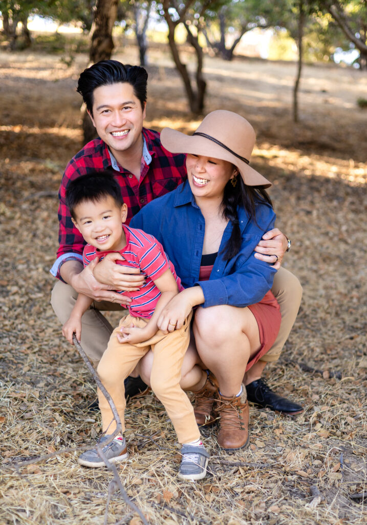 A playful family portrait of four climbing a tree, guided by a specialized Bay Area photographer during a mini session.