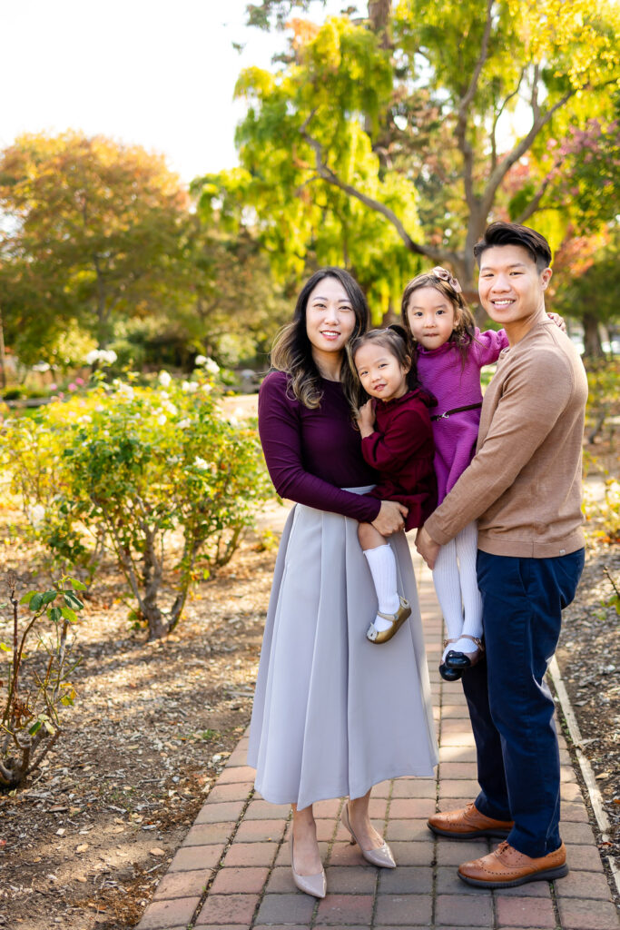 A family of four posing under golden fall trees at Washington Park.