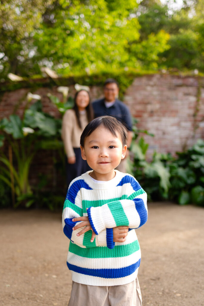 A young boy laughing and running along a garden path during a fall mini session.
