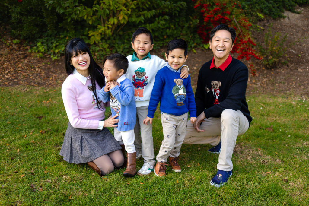 A large family of seven posing together in an open grassy meadow in Millbrae.