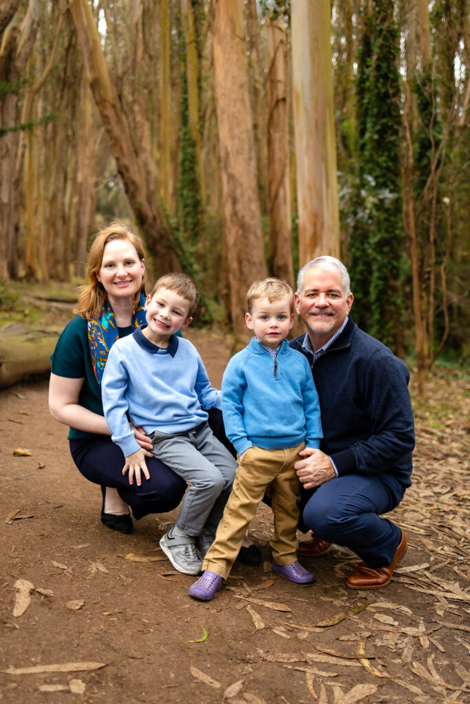 A family of four sitting on the wood logs at Lovers Lane with a San Francisco family photographer.