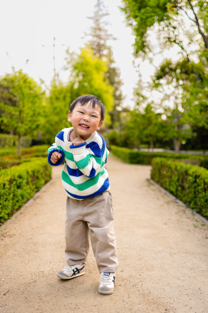 Close up shot of a smiling toddler boy wearing a striped sweater during a fall photoshoot.