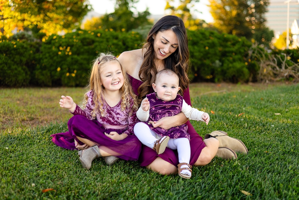 Mother and daughters wearing coordinating burgundy dresses during family portraits