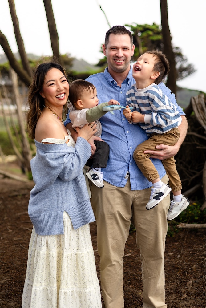Family wearing coordinated blue and cream clothing during a coastal family session