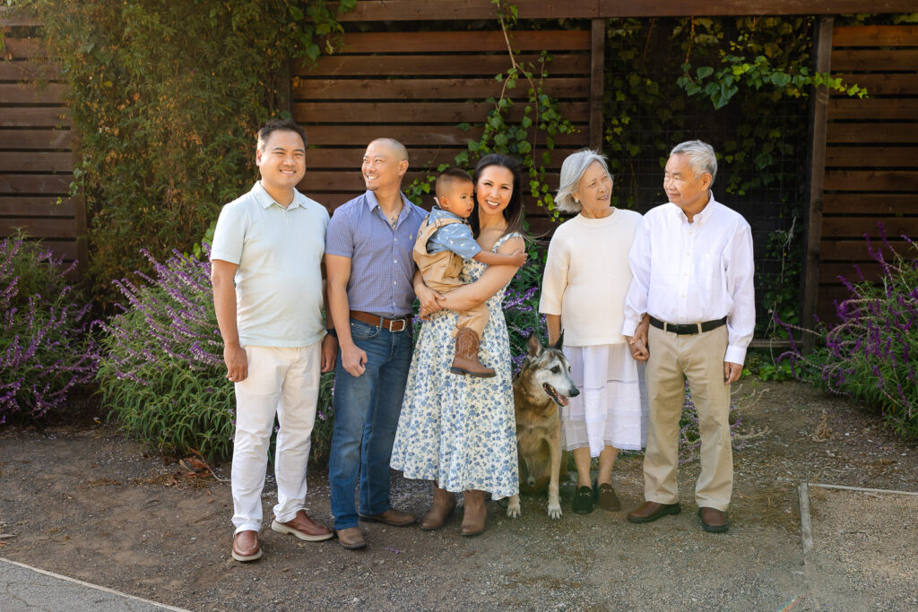Large group family photo color schemes with grandparents, parents, and toddler wearing coordinated white and khaki outfits during an extended family photoshoot.