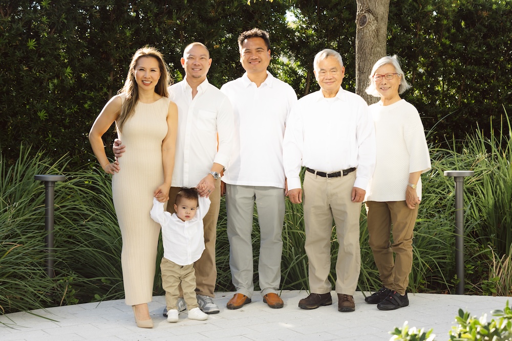 Large group family photo color schemes featuring a three generation family portrait with grandparents, parents, and toddler wearing a coordinated white and khaki color palette.