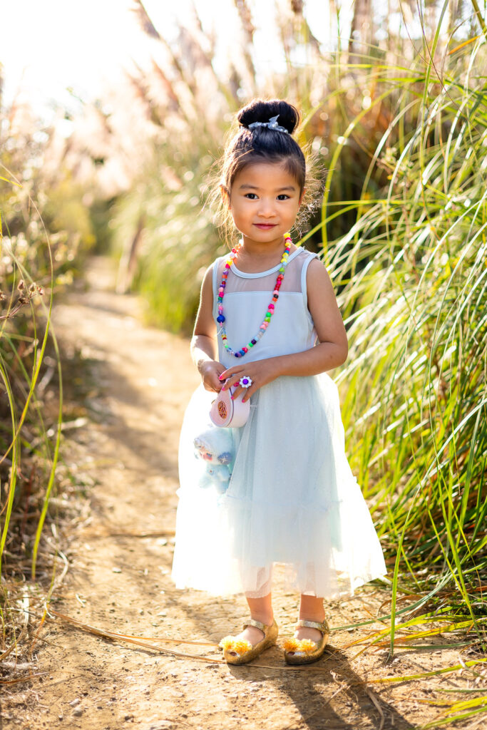 Young girl standing along a trail surrounded by pampas grass