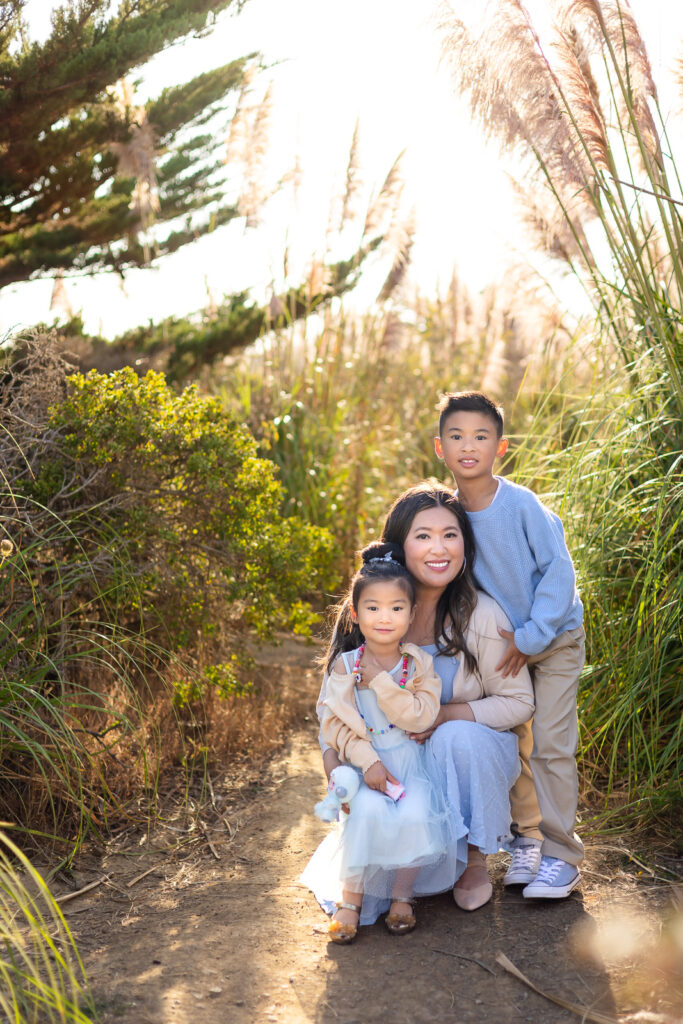 Mom and children hugging at golden pampas grass at sunset