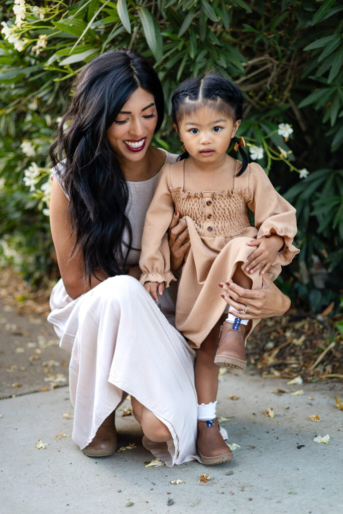 Mother holding her daughter beside blooming greenery