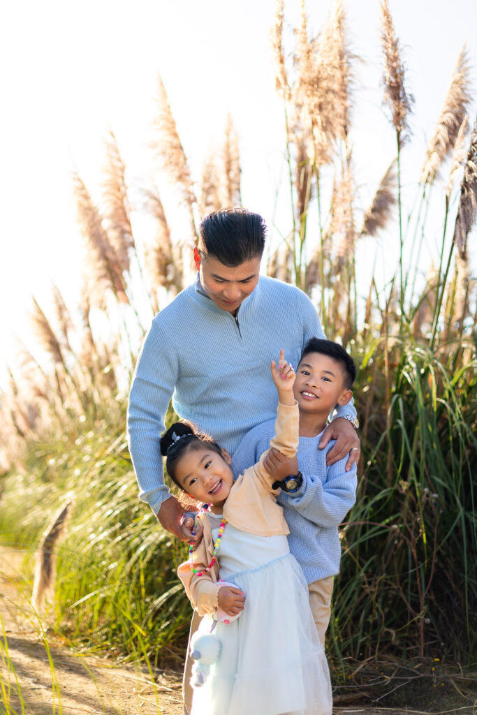 Father and children walking through golden pampas grass at sunset