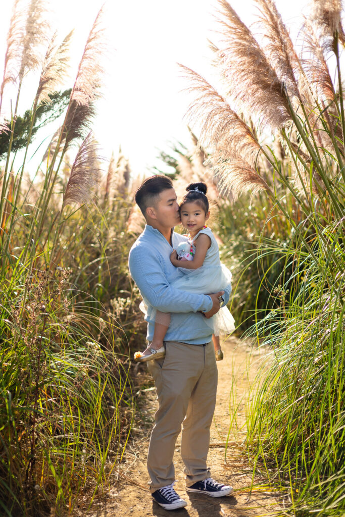 Father holding his daughter among tall pampas grass plumes