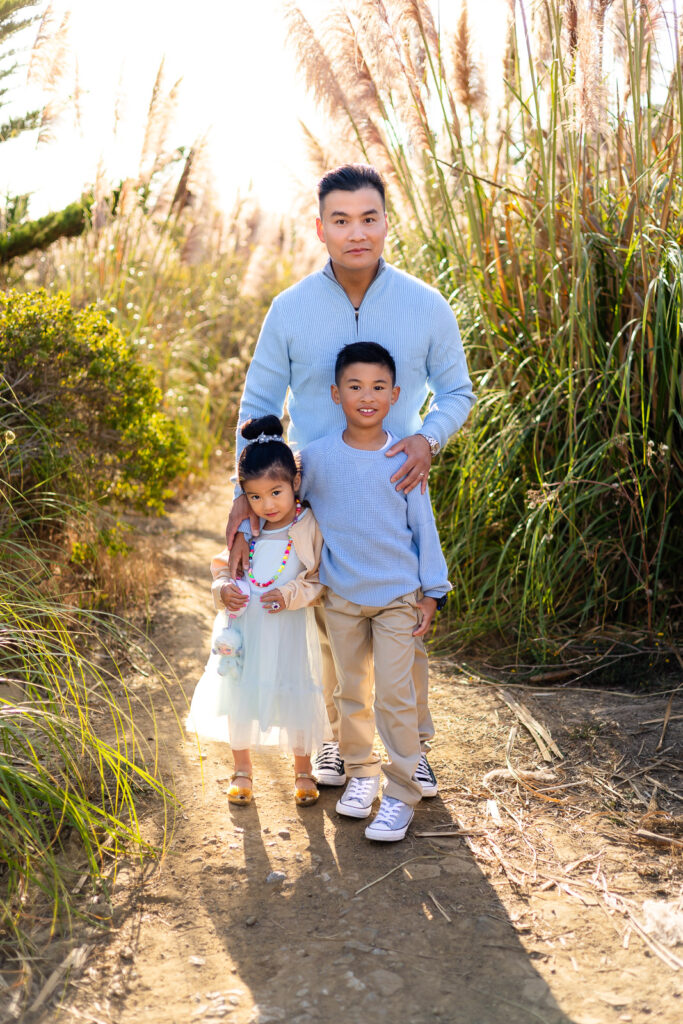 Father and children walking through golden pampas grass at sunset