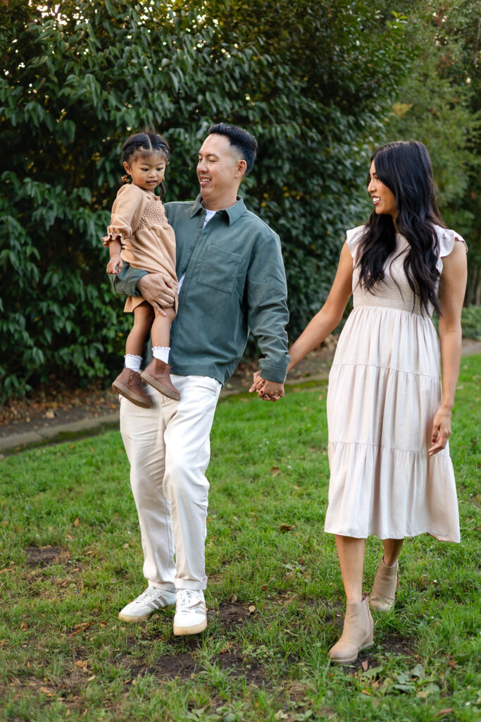 Parents holding their daughter beside blooming greenery