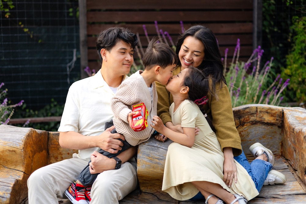 Brother and sister wearing neutral and yellow coordinated outfits while sitting on a wooden bench