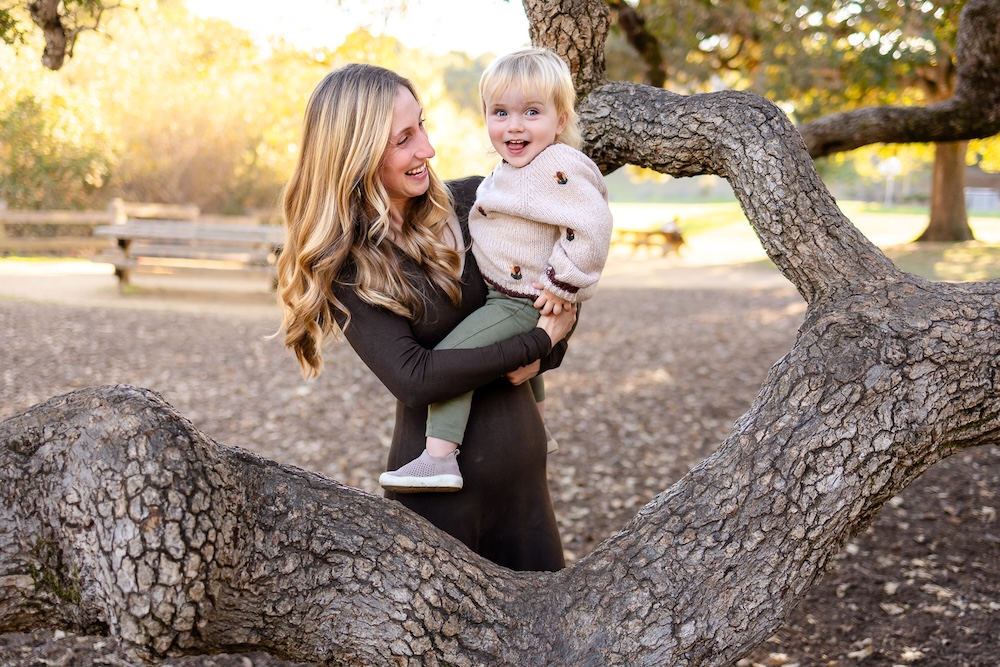 Mother holding toddler wearing earth tone clothing during an outdoor session