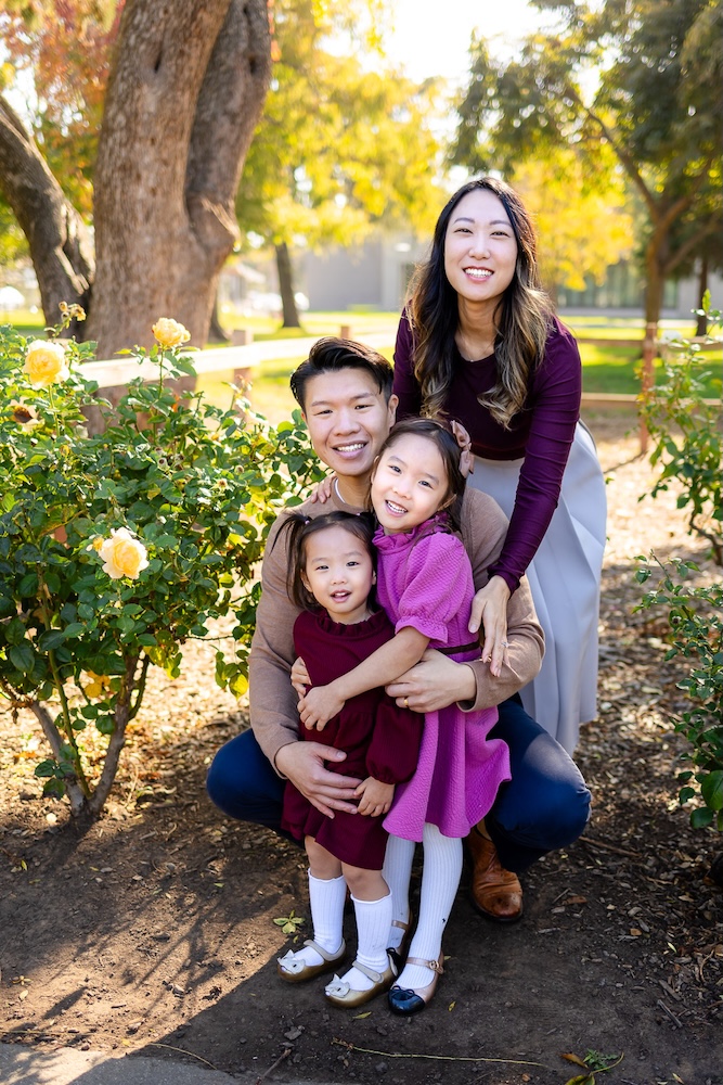 Family wearing burgundy, tan, and cream outfits in a fall garden setting