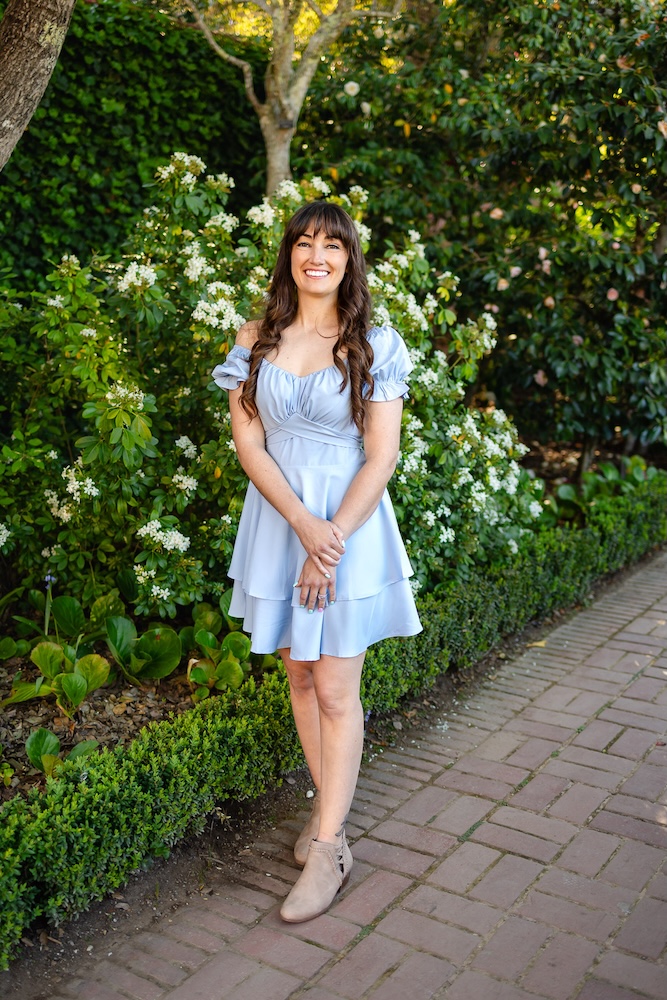 Senior wearing a light blue dress in a garden setting, an example of what to wear for senior portraits