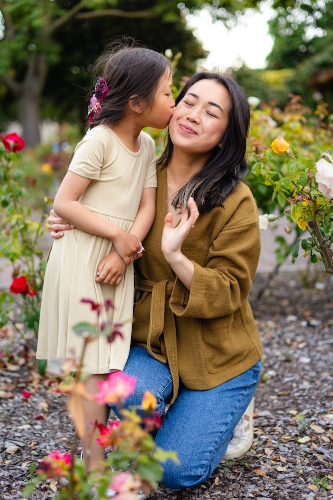 Mother receiving a sweet kiss from her daughter during an autumn photoshoot ideas session.