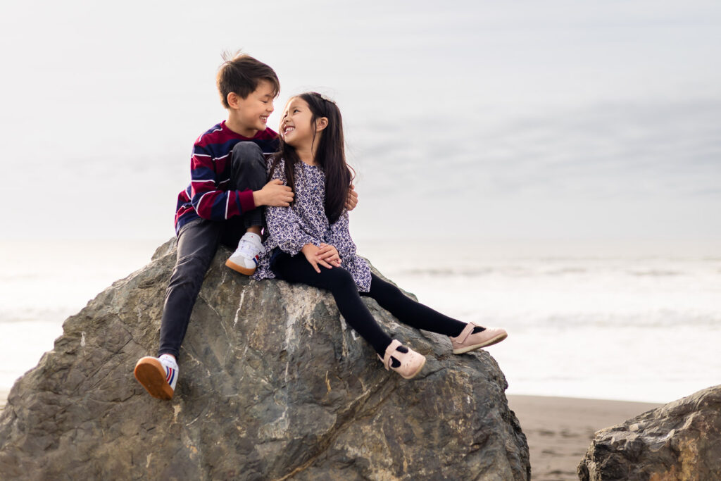 Young child sitting on coastal rocks during a family photo session at China Beach.