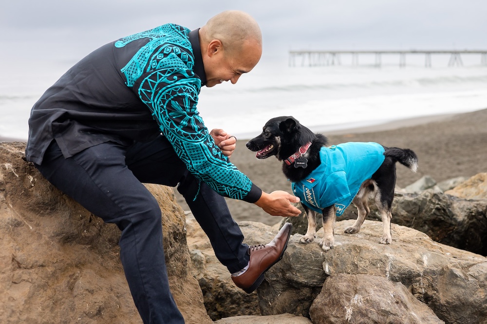 Owner playing with his rescue dog on coastal rocks during a relaxed portrait session.