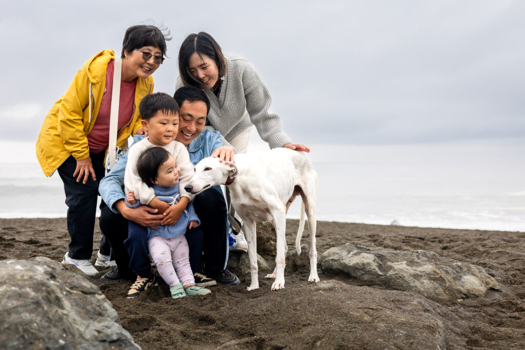 Extended family gathered together with their dog at Pacifica Beach.