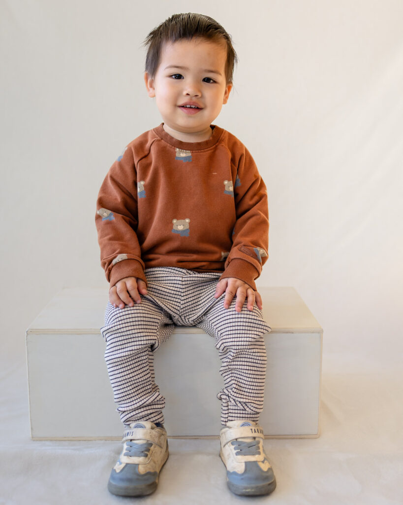 Toddler wearing a brown sweatshirt and striped pants for comfortable picture day outfits.