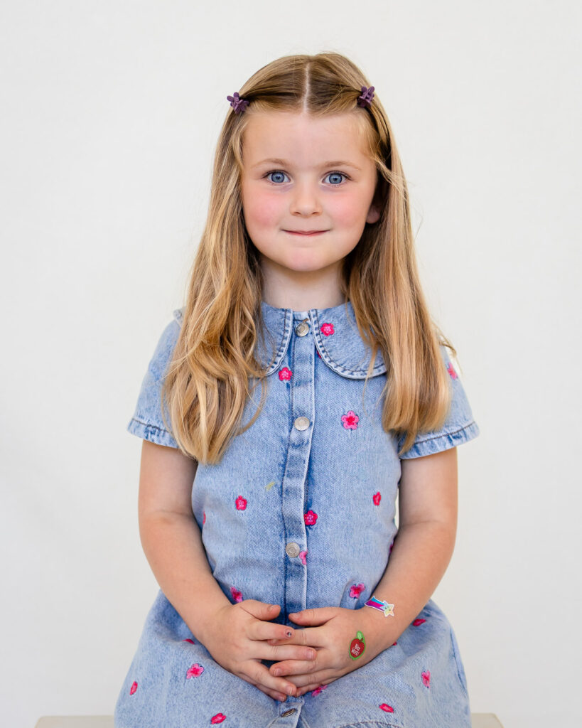 Young girl wearing a denim dress with floral details for stylish picture day outfits.