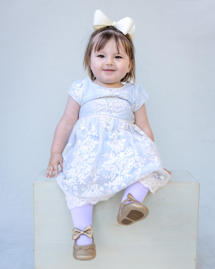 Toddler girl wearing a soft blue lace dress for a classic school portrait.