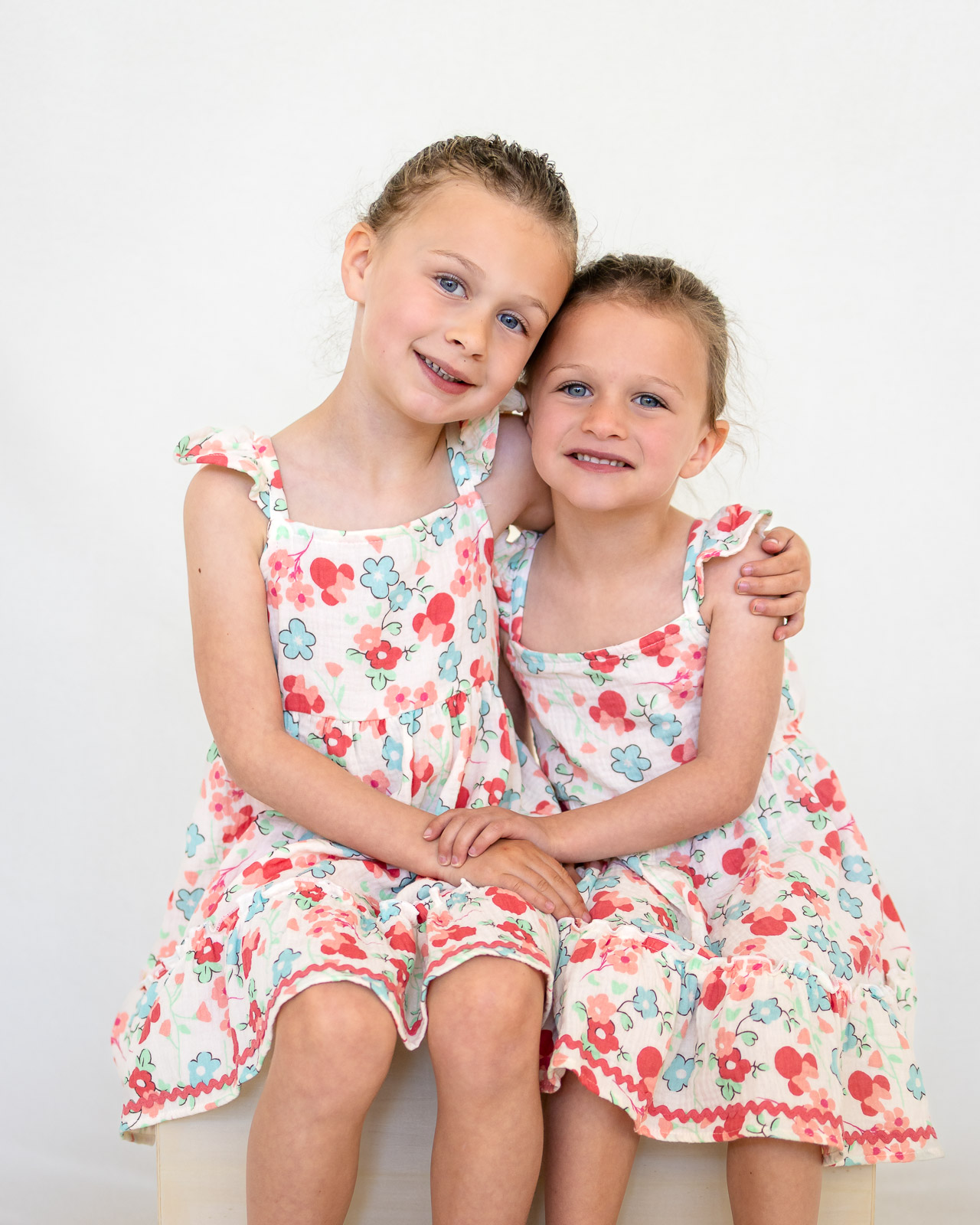 Sisters wearing matching floral dresses for coordinated school picture day portraits.
