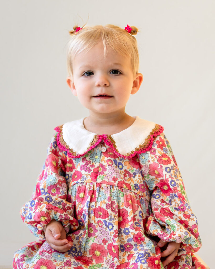 Toddler wearing a colorful floral dress with a classic Peter Pan collar for picture day.