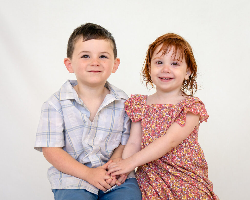 A brother and sister hold hands for a sibling portrait with a Bay Area school photographer.