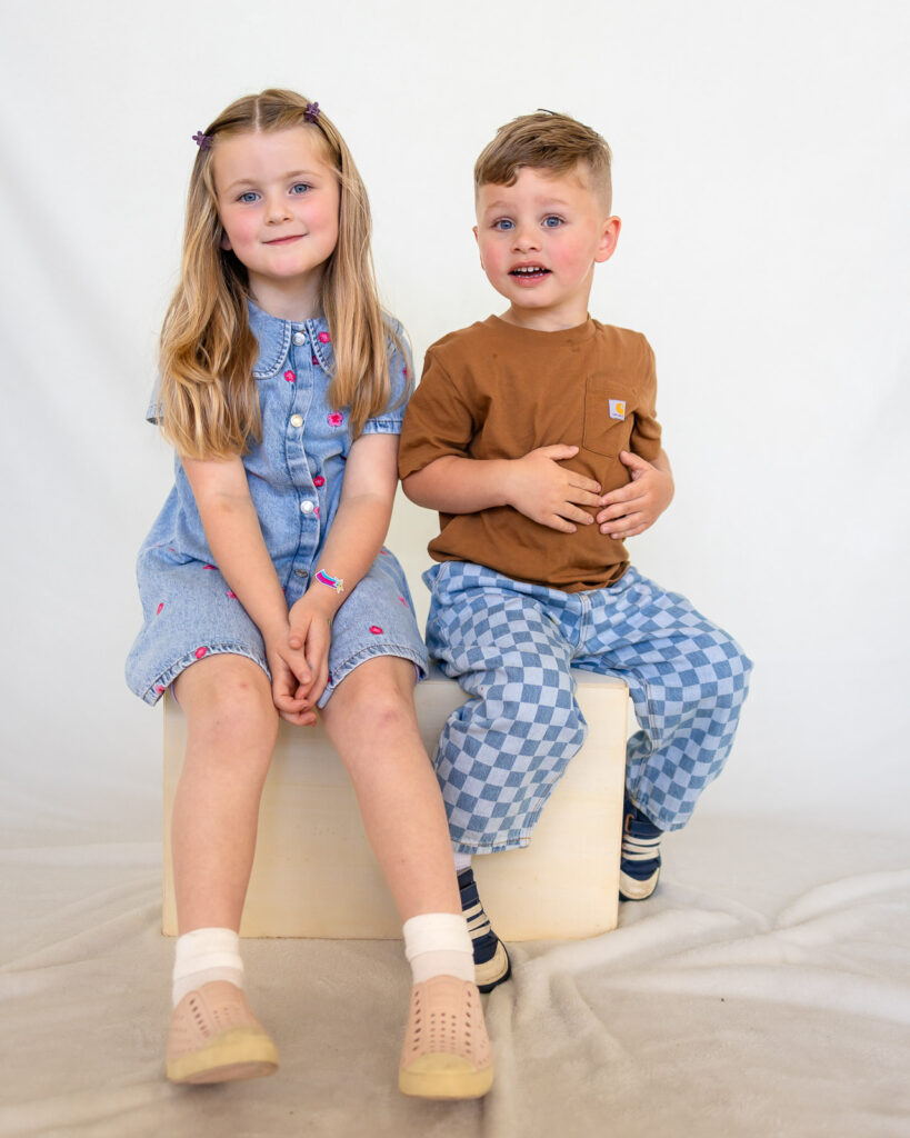 Two young siblings sit together for a preschool sibling portrait with a San Francisco preschool photographer.